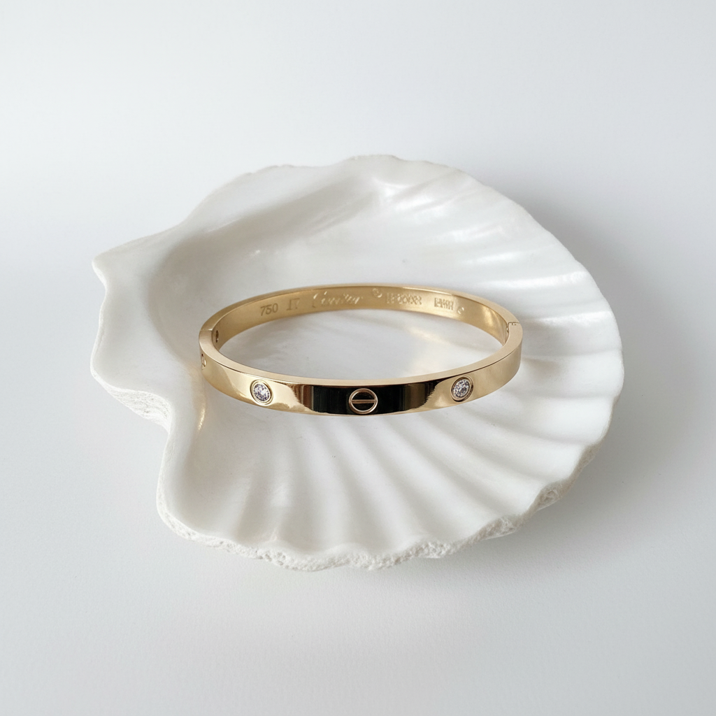 Wide love bangle bracelet flat lay on white shell tray minimal gold bracelet for women