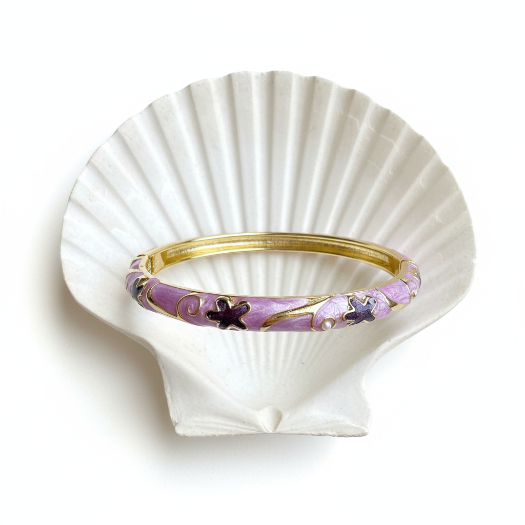 Flat lay of purple butterfly enamel bangle on shell tray