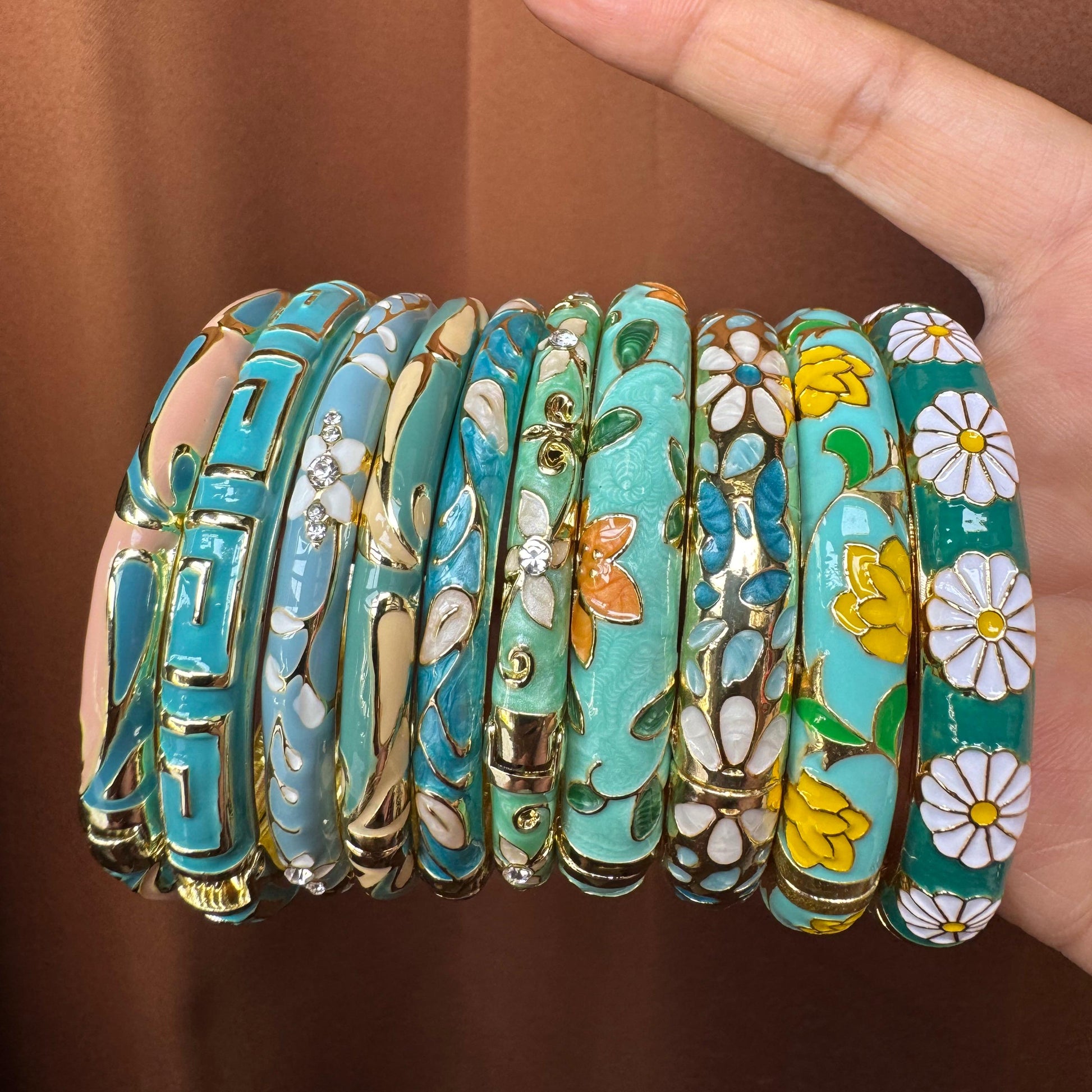 Set of floral-patterned bracelets on a hand against a brown background