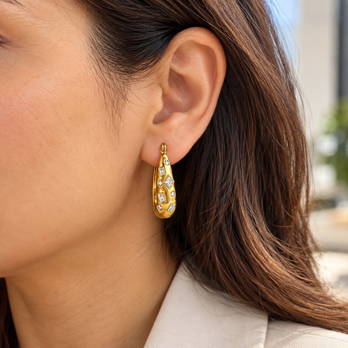 Elora gold crystal sculpted hoop earrings worn by a woman