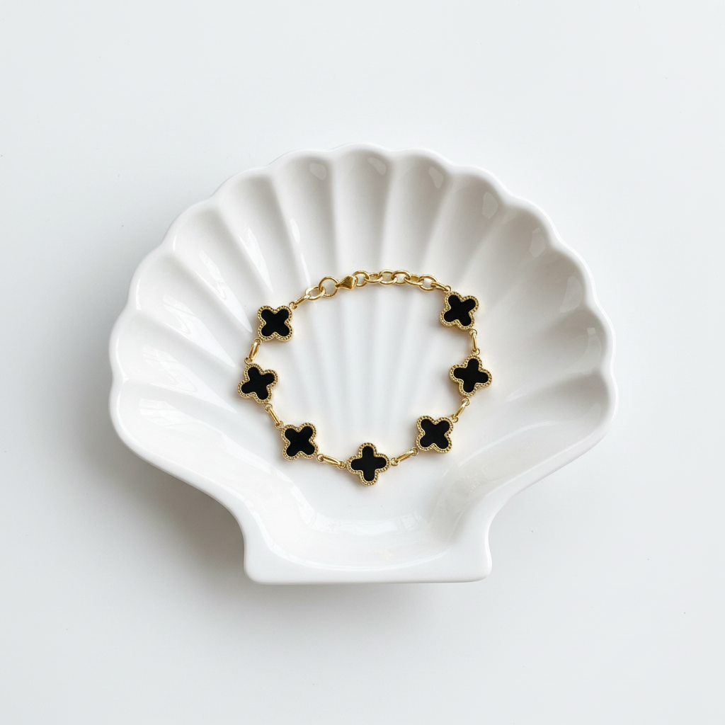 Flat lay of black clover bracelet in shell tray